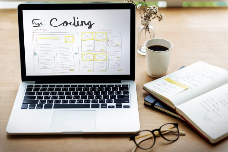 Laptop showing website wireframe and the word coding